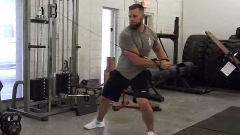 A person performing a cable woodchop exercise in a gym
