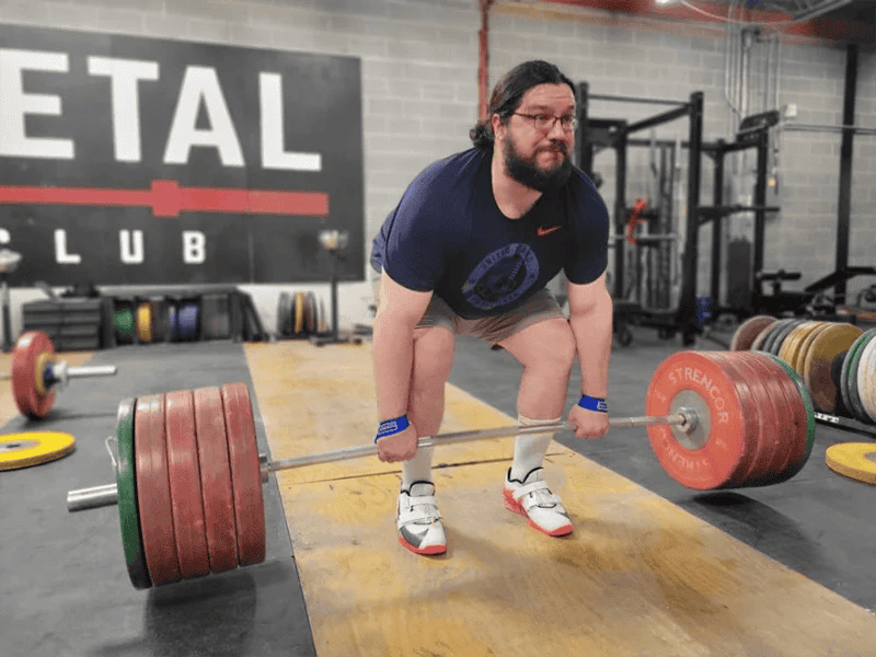 A person performing a deadlift with bumper plates in a garage gym