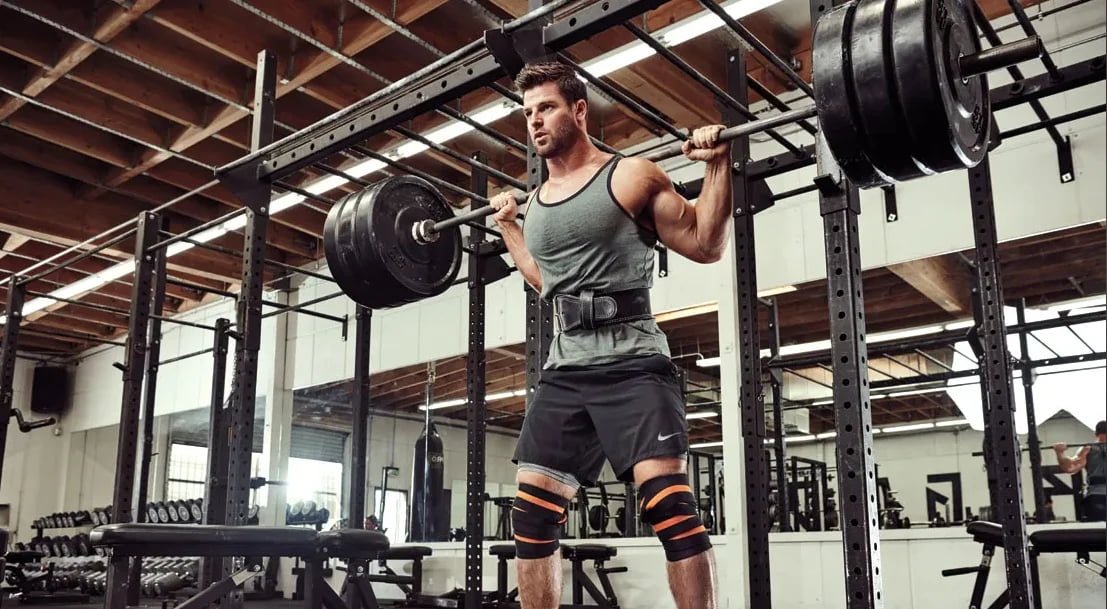 Adding Weight for Progressive Overload a close-up of weight plates being added to a rack