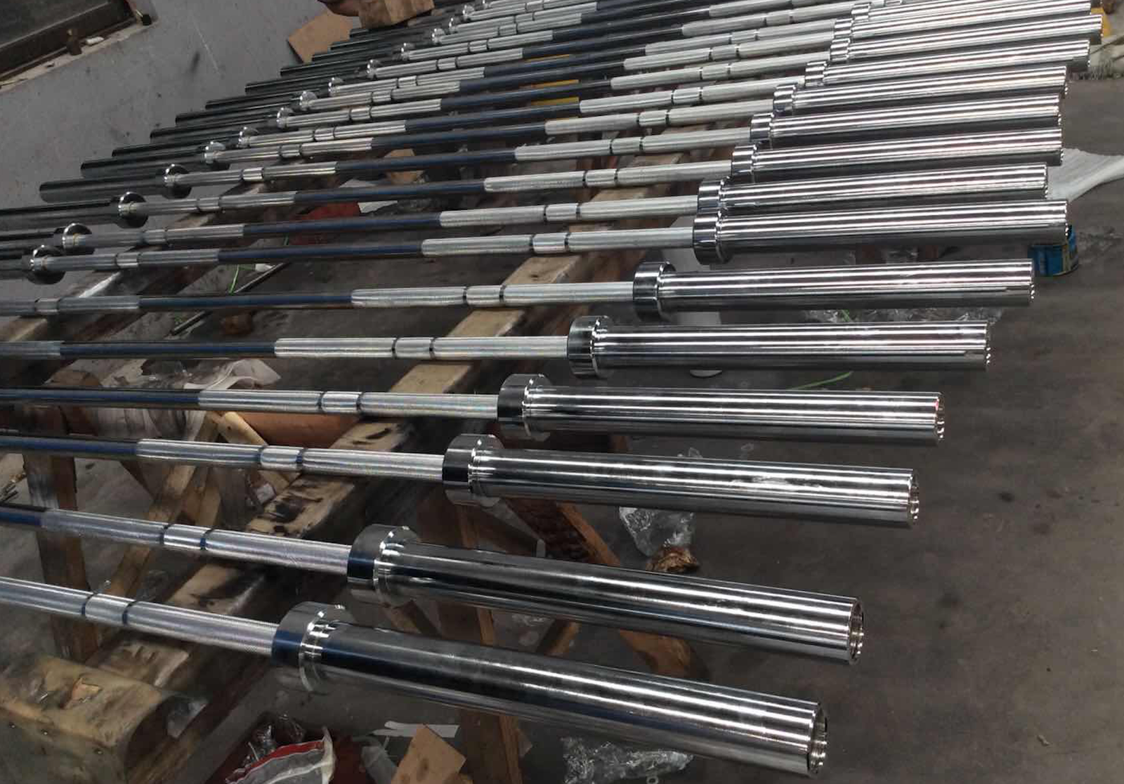 A collection of different barbells leaning against a gym wall