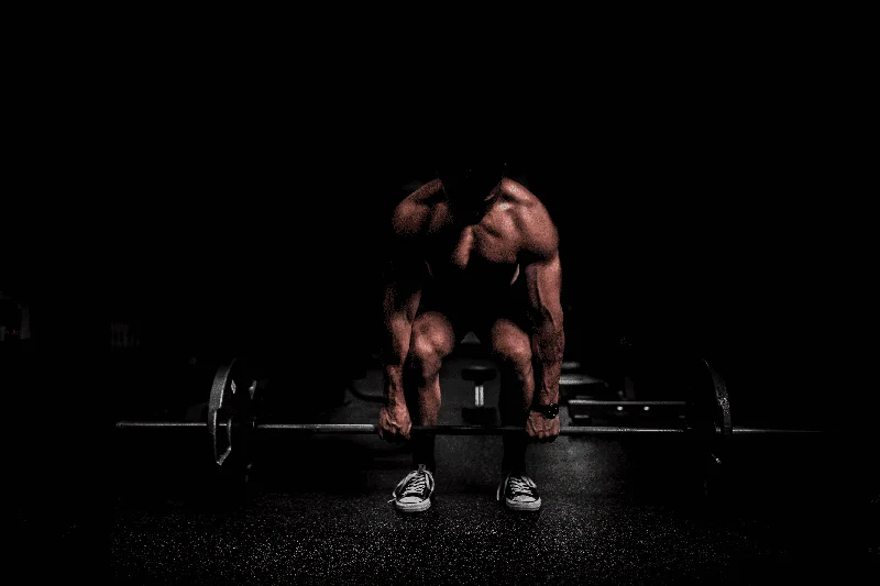 A muscular man performing a barbell row with correct form in a gym