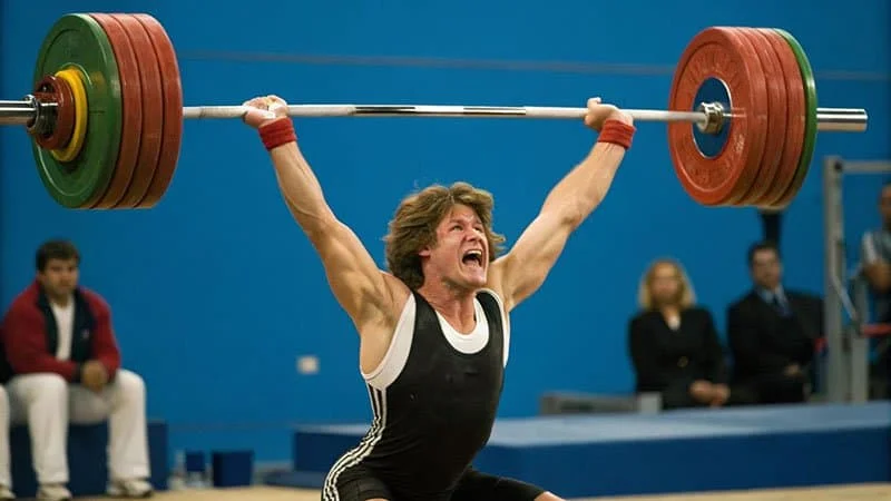 An athlete safely dropping a barbell loaded with bumper plates from an overhead position