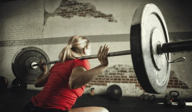 Woman performing a barbell squat in a squat rack